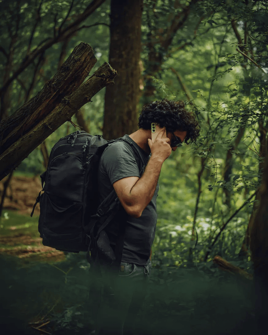 A caller taking a call outdoors, mid-hike